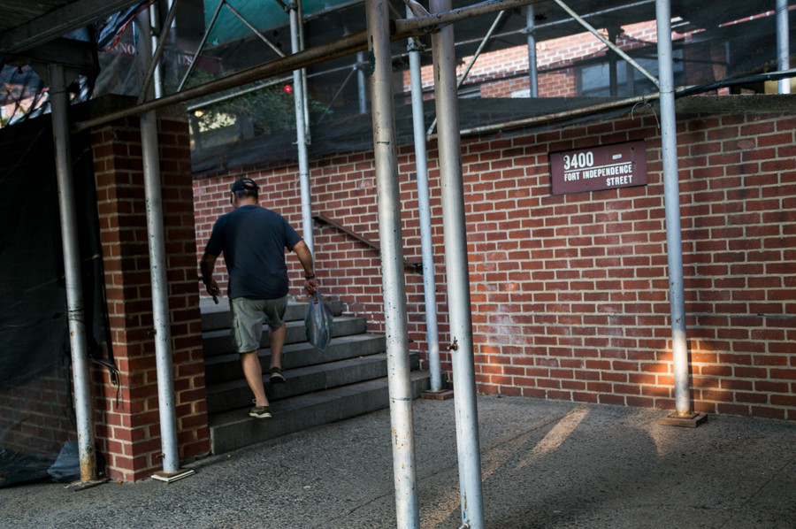 A pedestrian walks under the scaffolding at 3400 Fort Independence St.