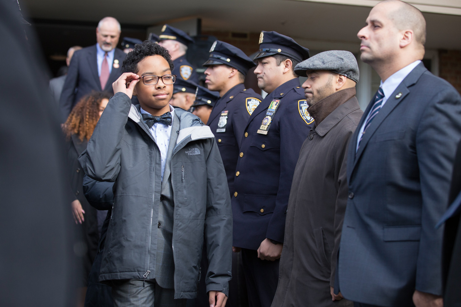 New York Police Department officers stand at attention as Peter Vega, son of the late Miosotis Familia, leaves a news conference where he and his sisters were given a home at Skyview-on-the-Hudson.