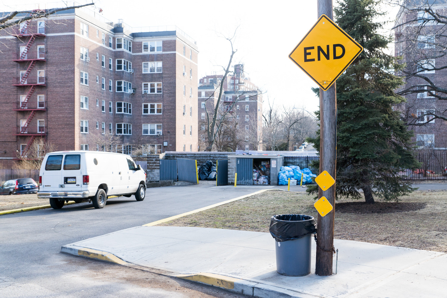 A sign warns pedestrians and motorists of a dead end on Netherland Avenue between West 256th and West 254th streets, where a row of dumpsters and a cinderblock wall blocks access. The North Riverdale Merchants and Business Association is one of the groups pushing to extend sidewalks, creating a connector path that could make it easier for pedestrians.
