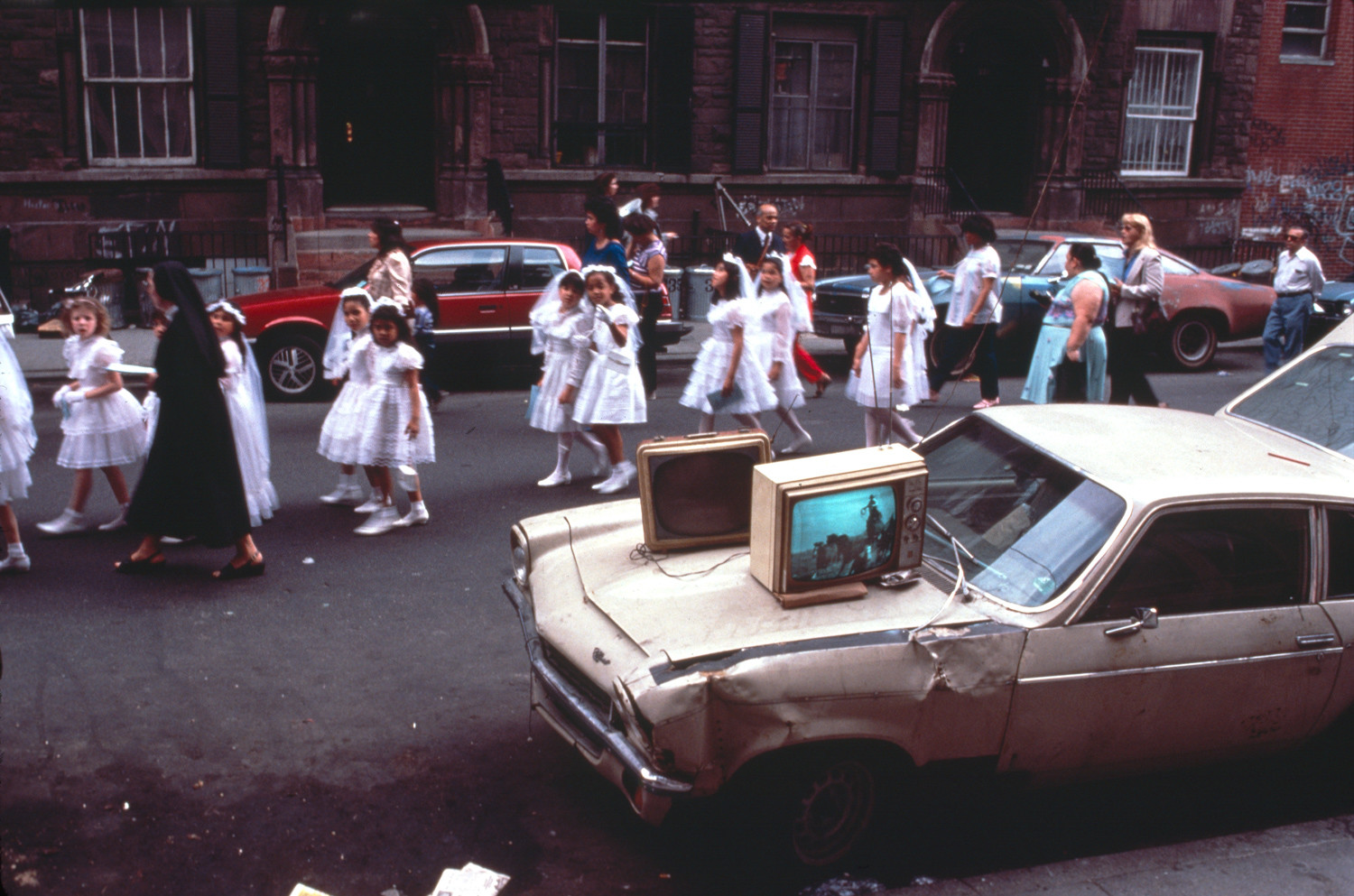 In this image, ‘Communion,’ from the early 1980s, Arlene Gottfried captured the intersections of life on a New York City street. A retrospective of Gottfried’s work, ‘A Lifetime of Wandering,’ is on display at Daniel Cooney Fine Art until April 28.
