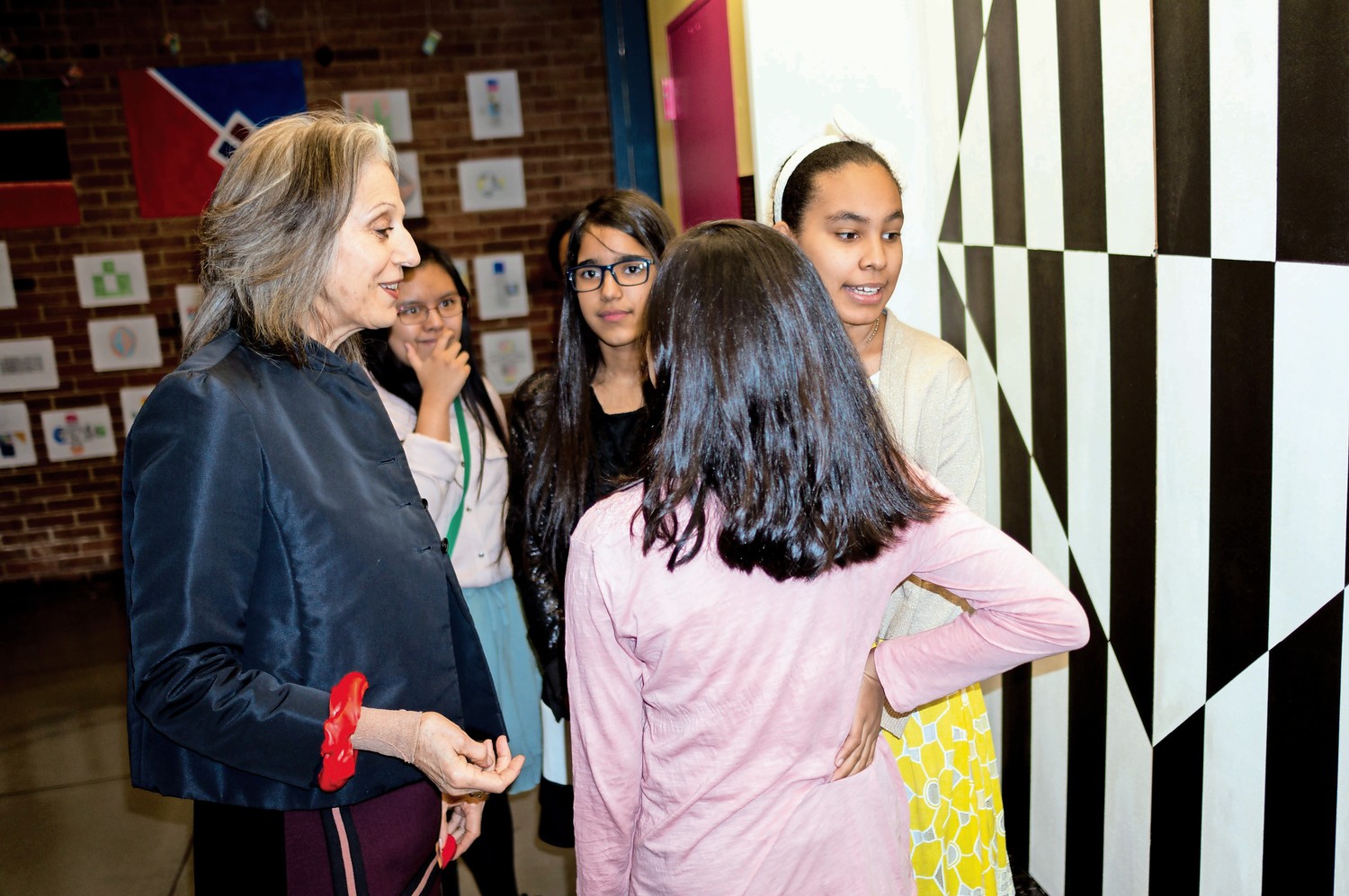 Ruth Lande Shuman, the founder of Publicolor, left, talks to students at M.S. 244 in front of a mural inspired by the work of Carmen Herrera. Publicolor worked closely with students at M.S. 244 to reproduce one of Herrera's paintings.