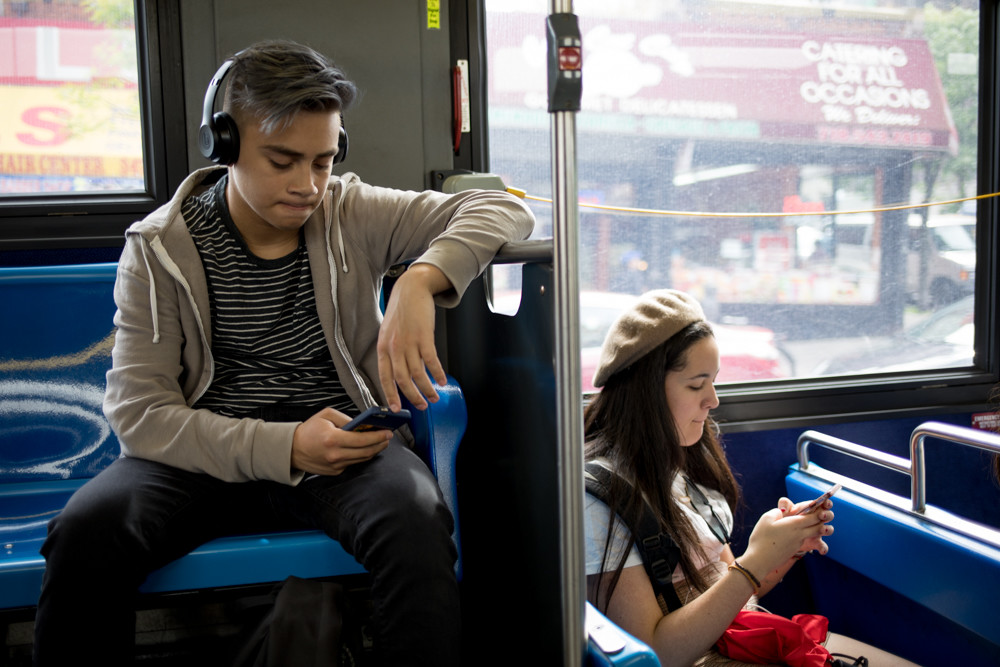 Passengers scroll through their phones on a Bx10 bus. Delays — not to mention overcrowding and bus bunching, when multiple buses serving the same line arrive at the same time — make for perhaps more scroll time than most passengers would prefer. One lawmaker’s plan to add shuttles might help.