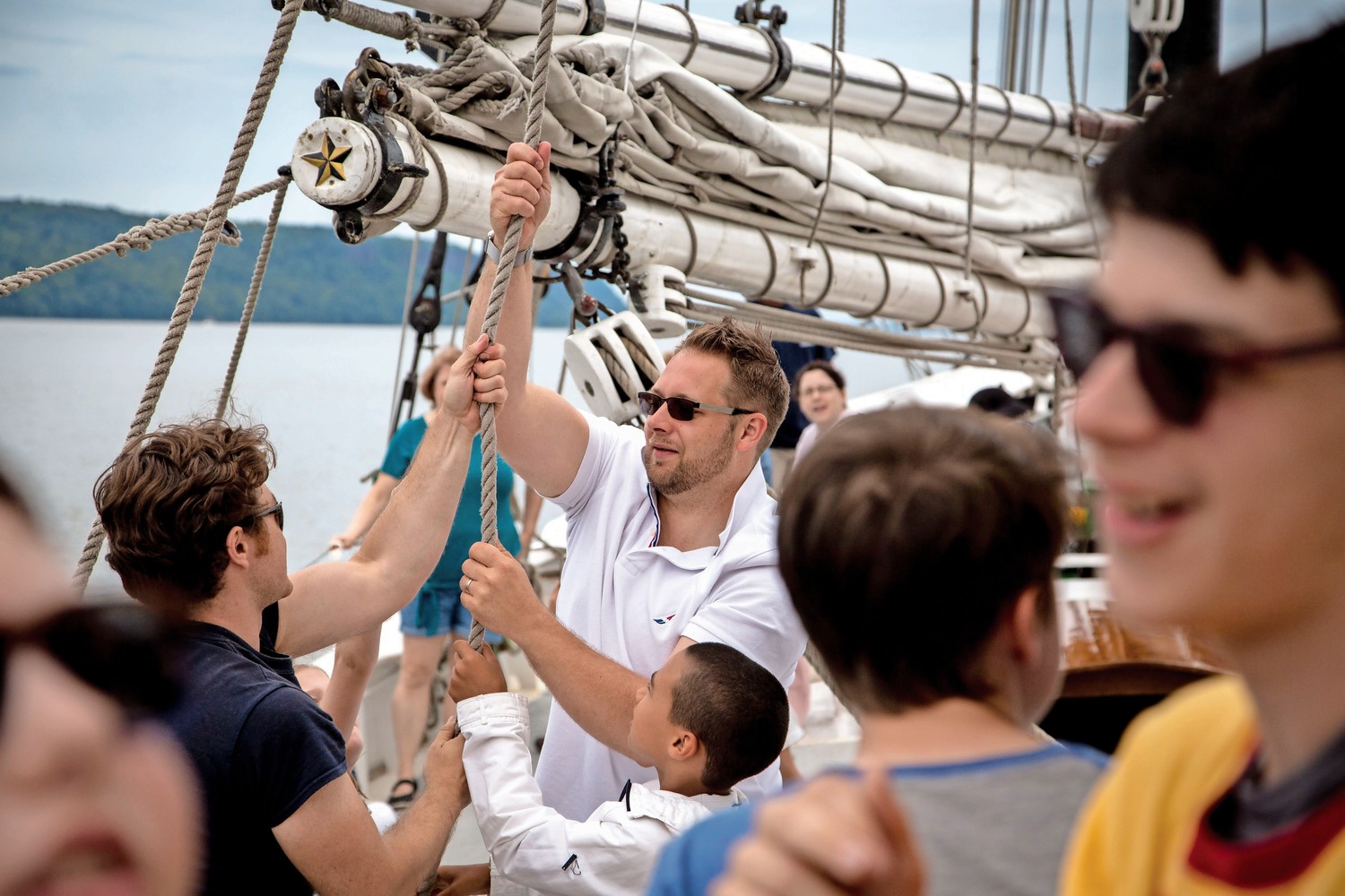 Crew members on the Pioneer schooner show would-be sailors how to raise the sails during RiverFestBX.