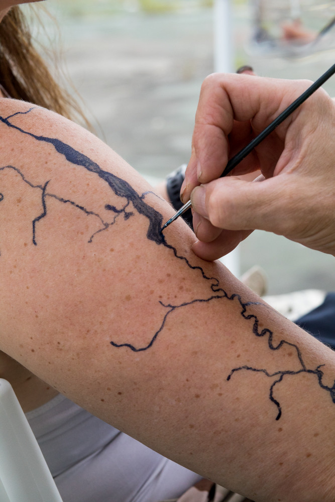 Bob Braine draws a temporary tattoo of an estuary at the launch event for Daylighting Tibbetts Brook, an initiative to bring attention to the ecology of Tibbetts Brook, a now-buried stream in the northwest Bronx that once connected Van Cortlandt Lake and Spuyten Duyvil Creek.