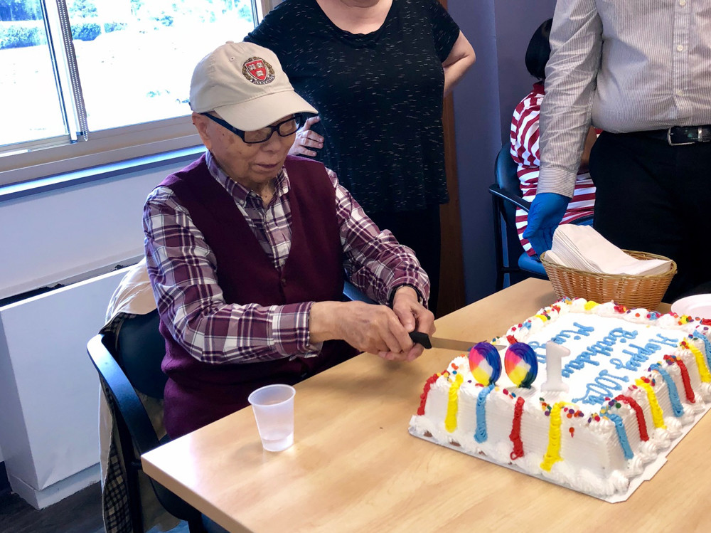 Ming Chin cuts into his birthday cake at Riverdale Senior Services. Chin, who celebrated his 100th birthday Aug. 27, suffers from Chin has early dementia and attends the adult day program for early memory loss at RSS nearly every week.