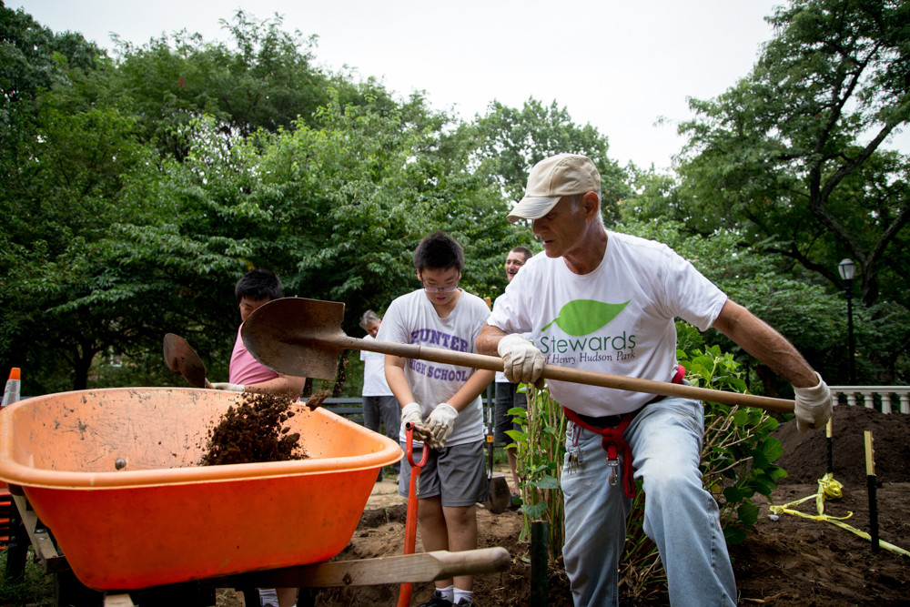 Mark Mason, a co-founder of the Stewards of Henry Hudson Park, drops soil in a wheelbarrow.