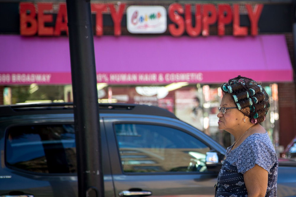 In his photographs, Eian Kantor looks for often humorous juxtapositions, as in the case of a woman with her hair full of curlers across the street from Cosmo Beauty Supply on Broadway.