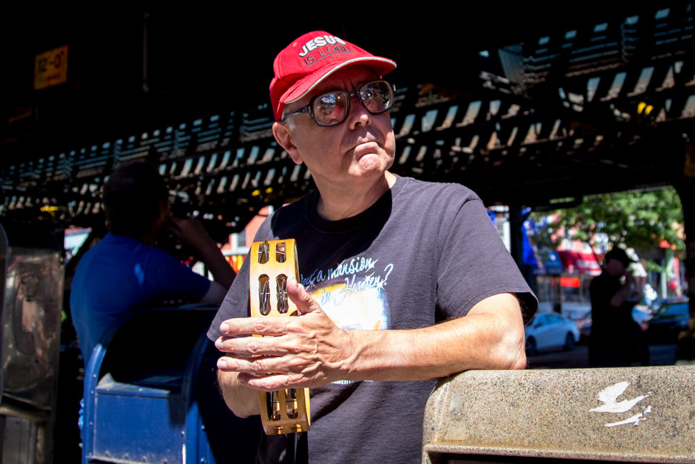 A street evangelist takes a break with tambourine in hand on Broadway.