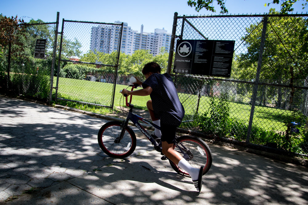 A kid zooms on his bicycle near Riverdale Playground.