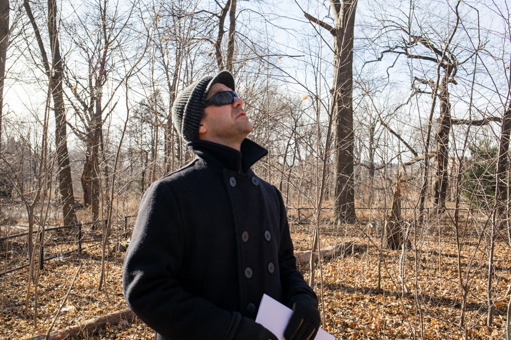 Kingsbridge Historical Society president Nick Dembowski looks up at the trees surrounding a colonial-era gravesite in Van Cortlandt Park. The gravesite is a short walk from a spot where skeletons were unearthed in the early 20th century along the Putnam Trail believed to have belonged to African-American slaves.
