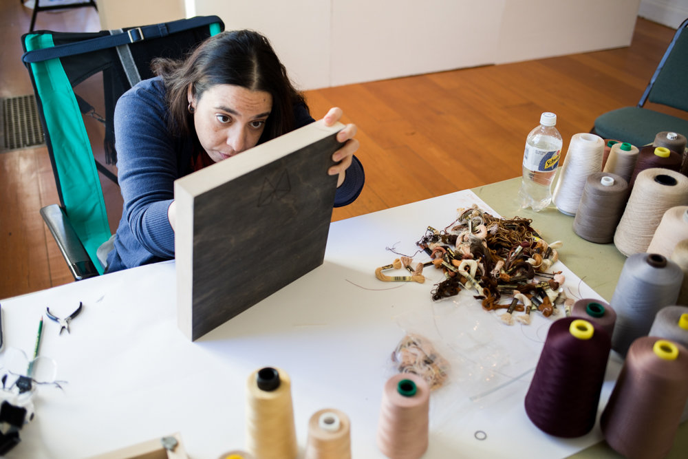 Melissa Calderón embroiders a piece of wood as part of her artistic practice in the Winter Workspace program at Wave Hill. Calderón seeks to merge her love of embroidering with wood, an unconventional material.