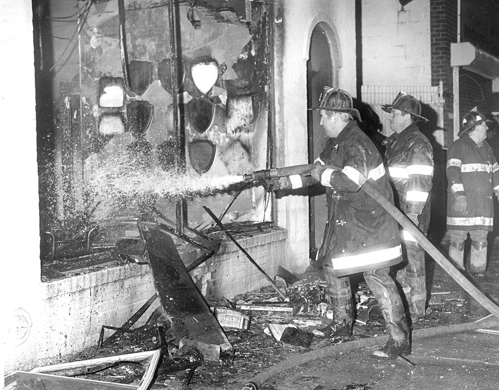 Firefighters use a hose to tackle the blaze through the newspaper’s front window.