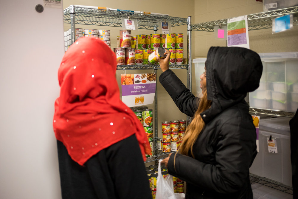 Lehman College senior Obiajulu Nwafor, right, selects some canned food with the help of classmate Daou Traore in the school’s food pantry. Traore is one of a number of food pantry volunteers.