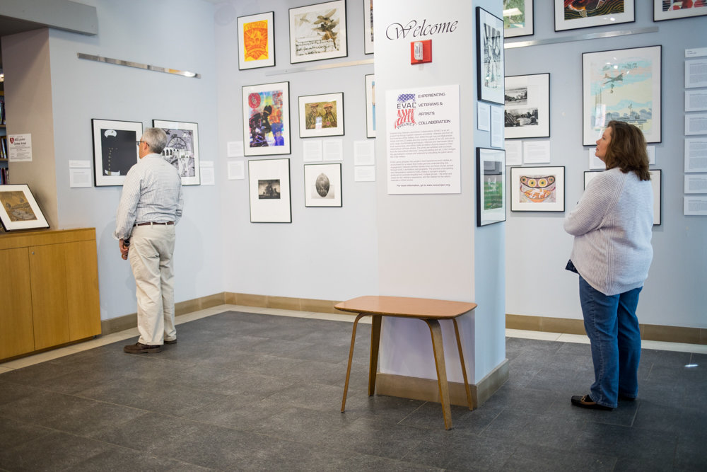 Visitors look at artwork in 'Experiencing Veterans and Artists Collaboration,' an exhibition on display at Manhattan College's O'Malley Library through June 21.