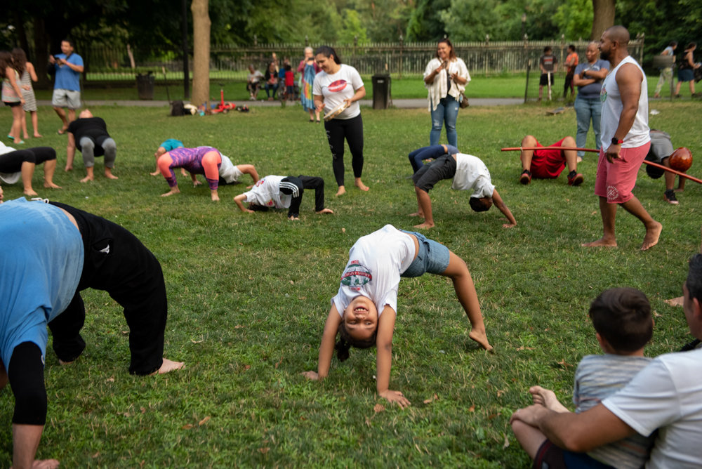 Children and adults practice backbends during an outdoor capoeira session in Van Cortlandt Park run by the owners of ABADÁ-Capoeira Bronx.