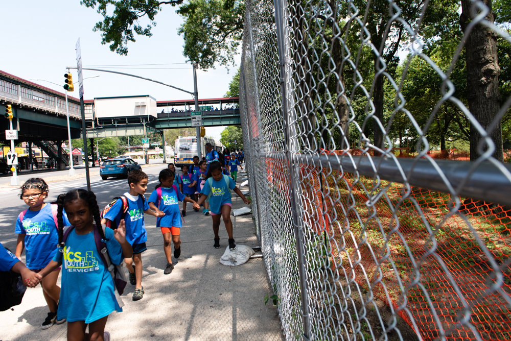 Children walk by a fence that encloses ongoing construction at Van Cortlandt Park.