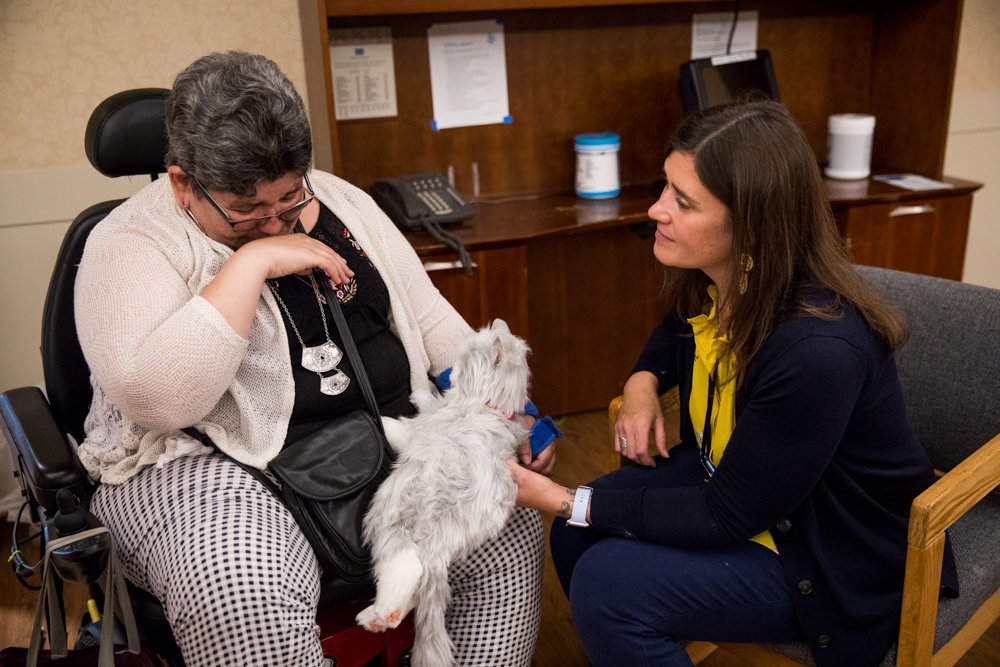 Elizabeth Pagan, left, cries as she holds a robot cat at the Hebrew Home at Riverdale. The Hebrew Home inaugurated its robot cat therapy program nearly four years ago to help residents with Alzheimer's disease and dementia. But the program has been a massive success even beyond those specific residents.
