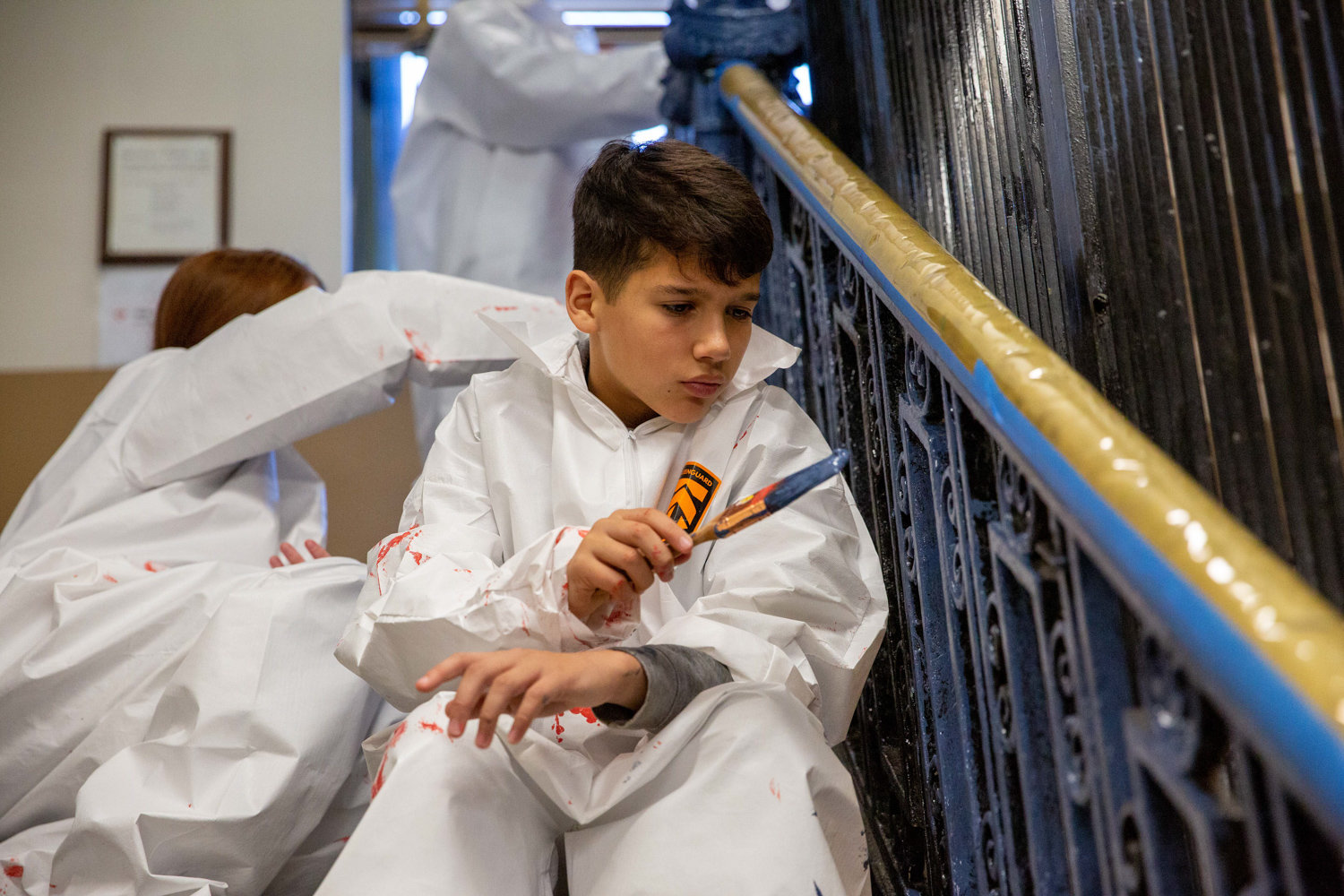 Logan Donato, son of Local Union No. 3 IBEW member Chris Donato, paints a banister inside the Kingsbridge Heights Community Center on Nov. 16. The union teamed up with Rebuilding Together NYC to fix up the center, including repainting, simple rewiring work and moulding replacement.