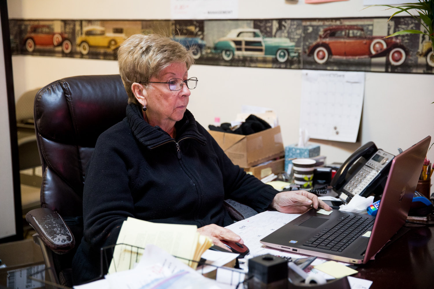 Irene Goldstein works on her computer inside Gotham Driving School, which she owns. Originally from Venezuela, Goldstein understands how the promise of a better life pulls people to the United States, but when someone walks through the door at her school, her focus is simply on getting them ready for the road.