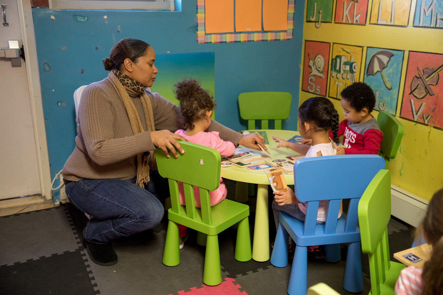 Michelle Weiss helps children work through puzzles at Rodi Daycare Center on Netherland Avenue. Despite the high price of child care citywide, Rodica Chiacu, the center’s owner, has worked to keep her rates affordable for parents.
