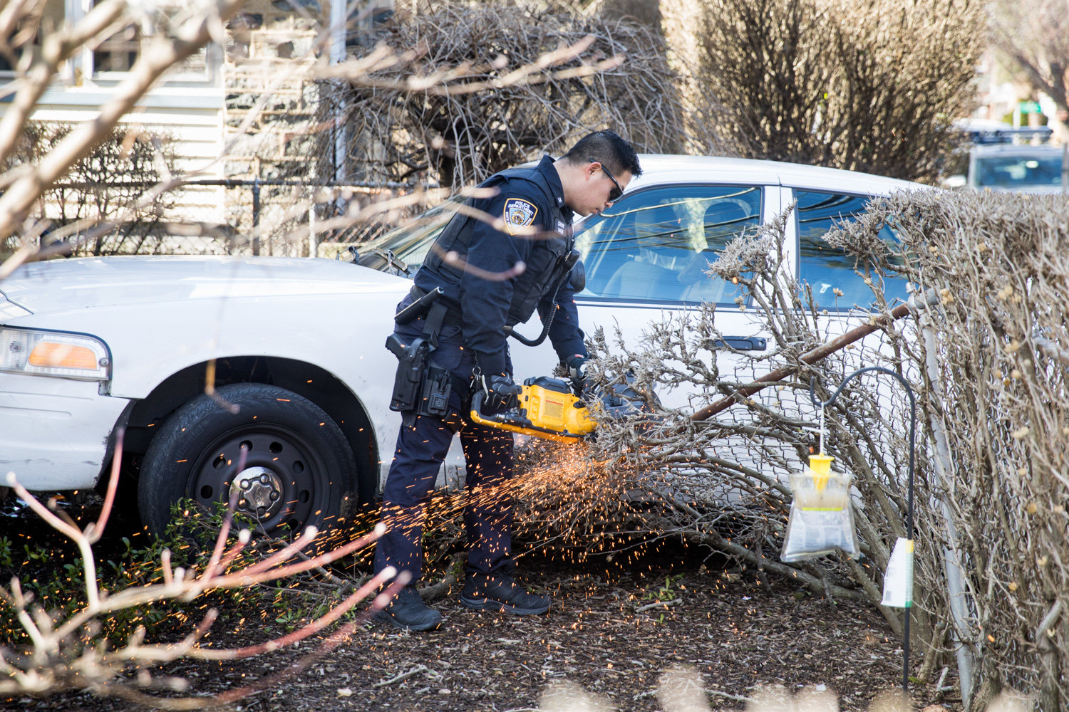 A police officer cuts away part of a wire mesh fence outside 400 W. 261st St., where a car crashed through the fence on the morning of Feb. 27,