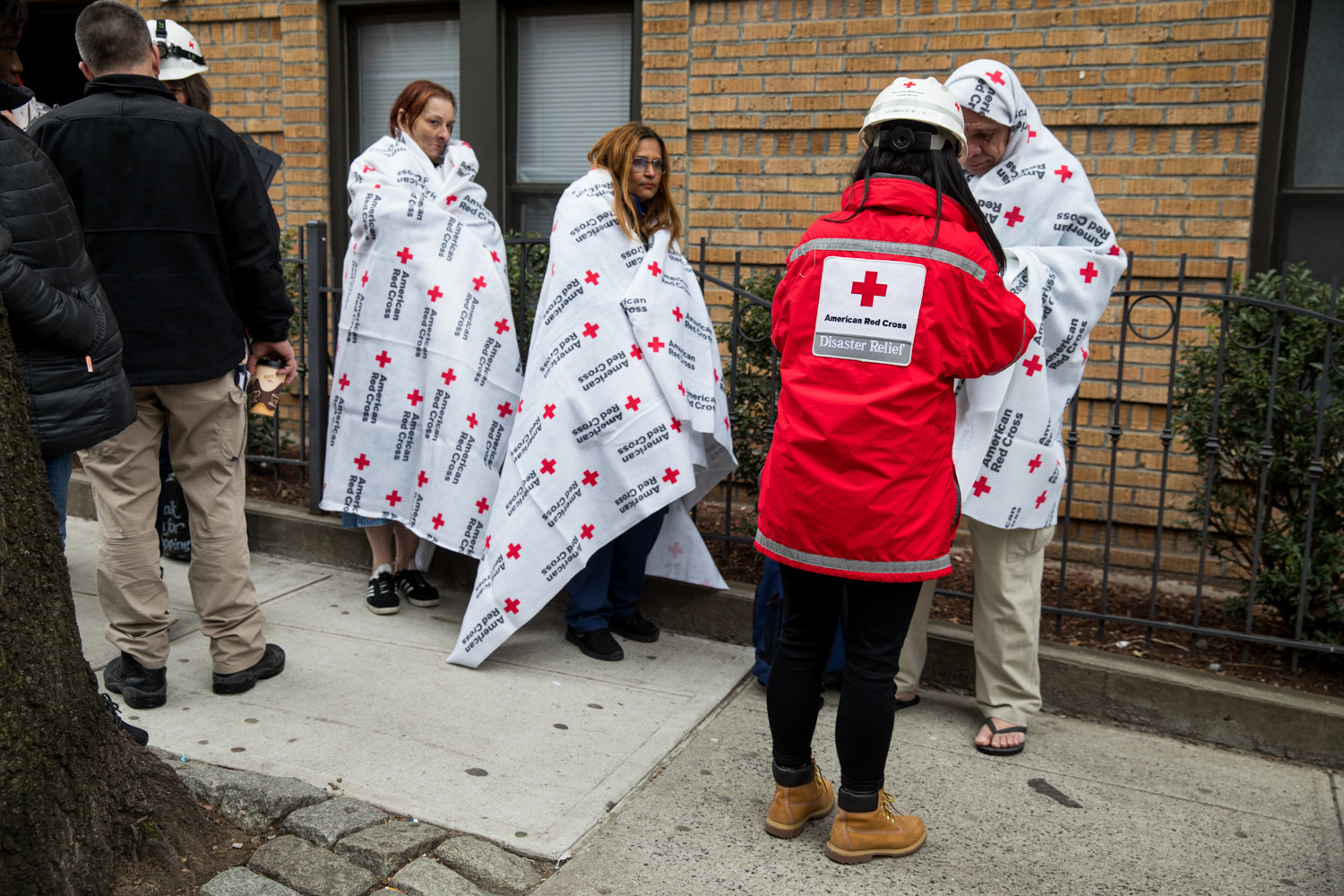 A member of the American Red Cross helps residents of 215 W. 242nd St., where a fire broke out Friday morning.
