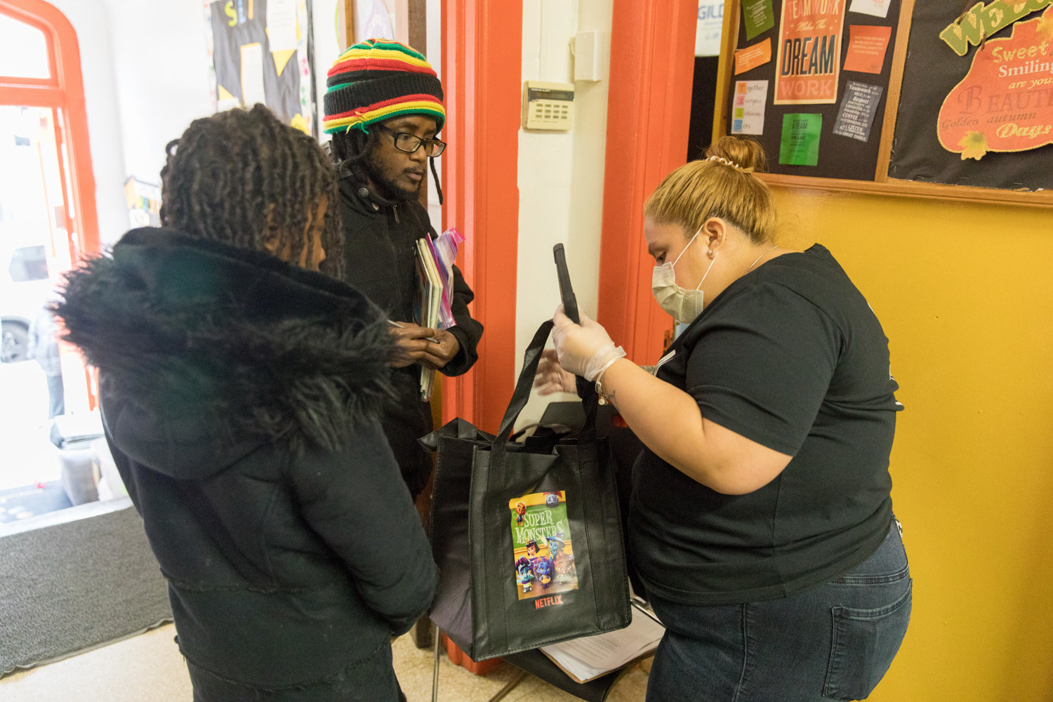 P.S. 207 aide Amy Jimenez hands bags of learning materials to Frederick Hay, the parent of three children enrolled at the Godwin Terrace school.