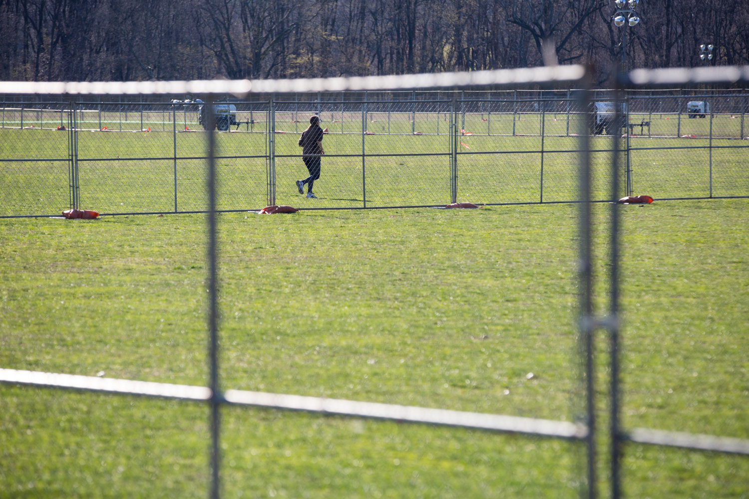 A park-goer jogs along the perimeter of a fenced-off portion of the Van Cortlandt Park Parade Grounds, which will be the site of a 200-bed COVID-19 field hospital.