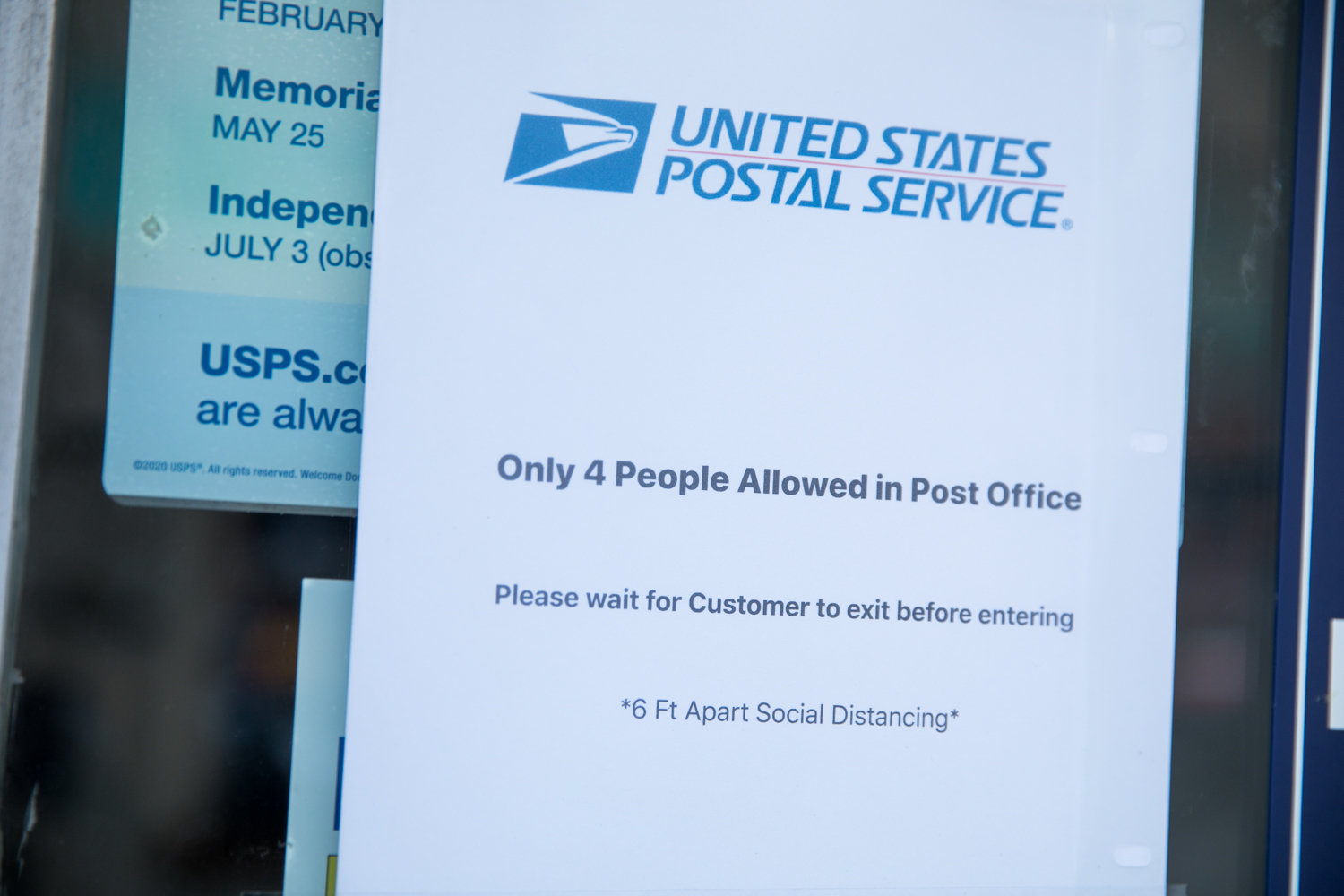 A sign informs people that due to social distancing guidelines caused by the coronavirus pandemic, only four people at a time are allowed inside the post office at 444 W. 238th St.