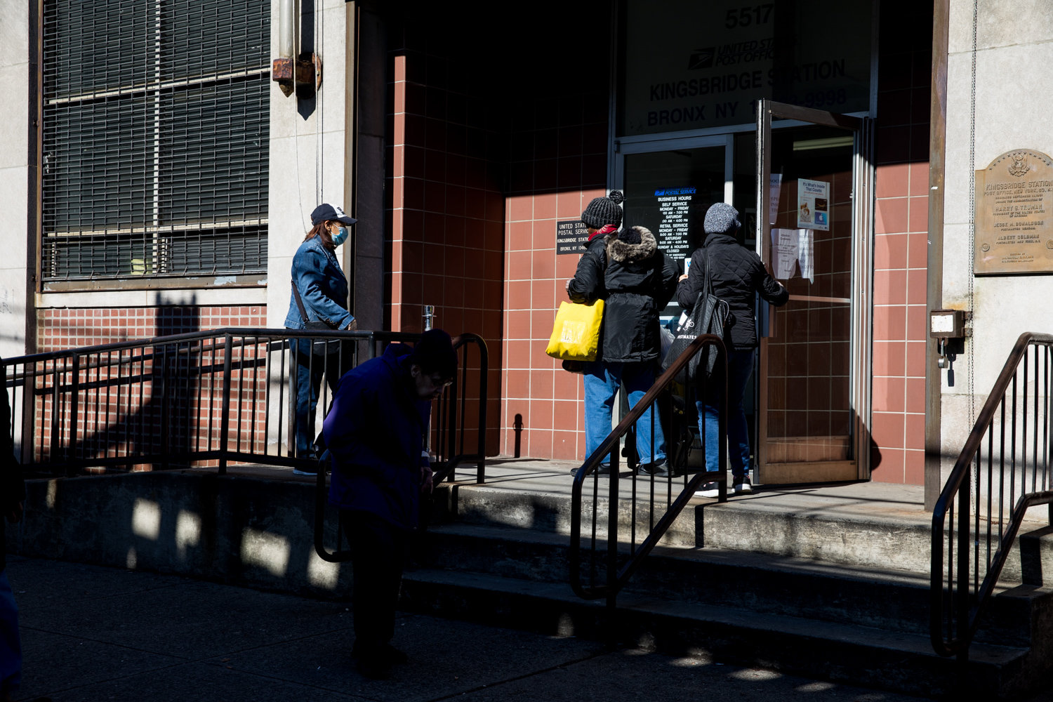 People enter and leave the post office on Broadway, which has recently suffered from understaffing — one of the reported causes of slowdown in mail delivery throughout the community.
