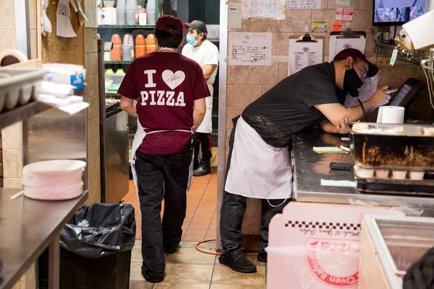 Jody DePasquale, manager of Addeo’s Riverdale Pizza, right, talks on the phone while filling an order shortly after opening. The North Riverdale pizza joint has managed to stay open when many others have shuttered, a consequence of the coronavirus pandemic.