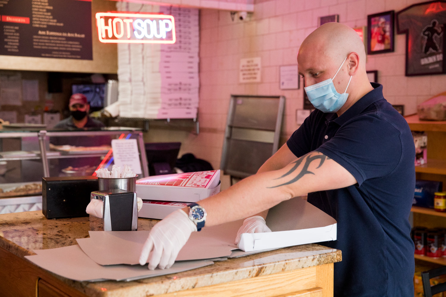 Mike Donkis folds pizza boxes inside Addeo’s Riverdale Pizza, which has managed to stay open during the coronavirus pandemic.