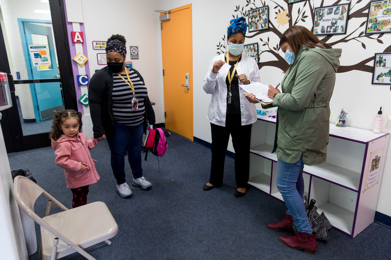 Roxana Vazquez, right, fills out a form while picking up her daughter Mia from The Learning Experience. It’s at that Riverdale Avenue facility where Mia receives free care by day while Vazquez works as a clinical social worker in Westchester County.