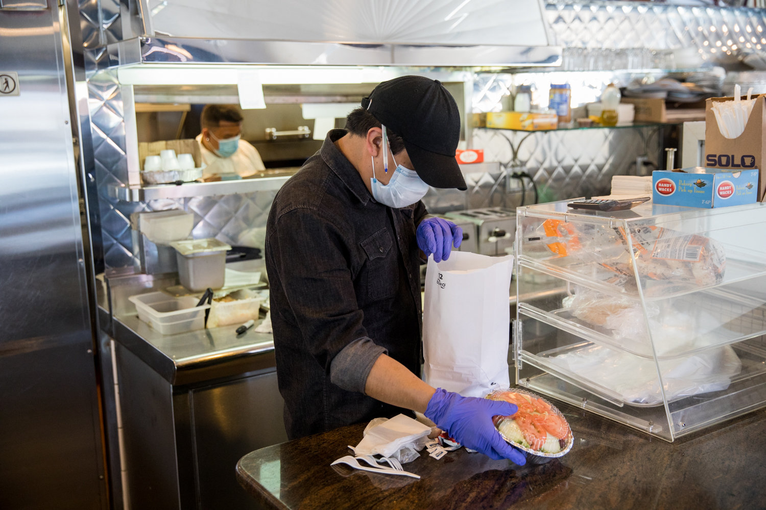 A worker bags an order at Tibbett Diner, which, like many small businesses, has suffered as a consequence of the coronavirus pandemic.