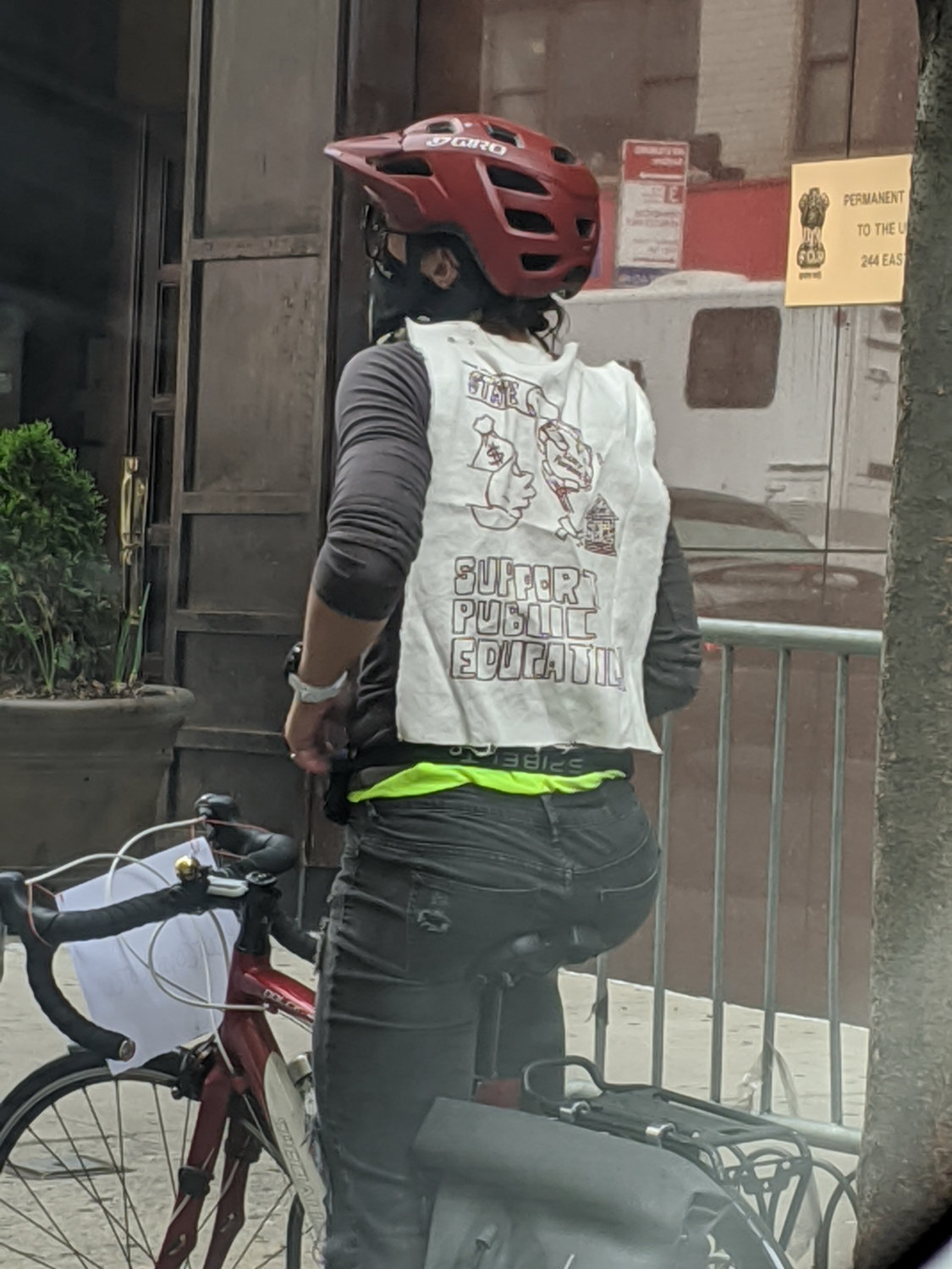 A cyclist wears a sign reading ‘support public education’ during a protest against layoffs at various schools within the CUNY educational system.