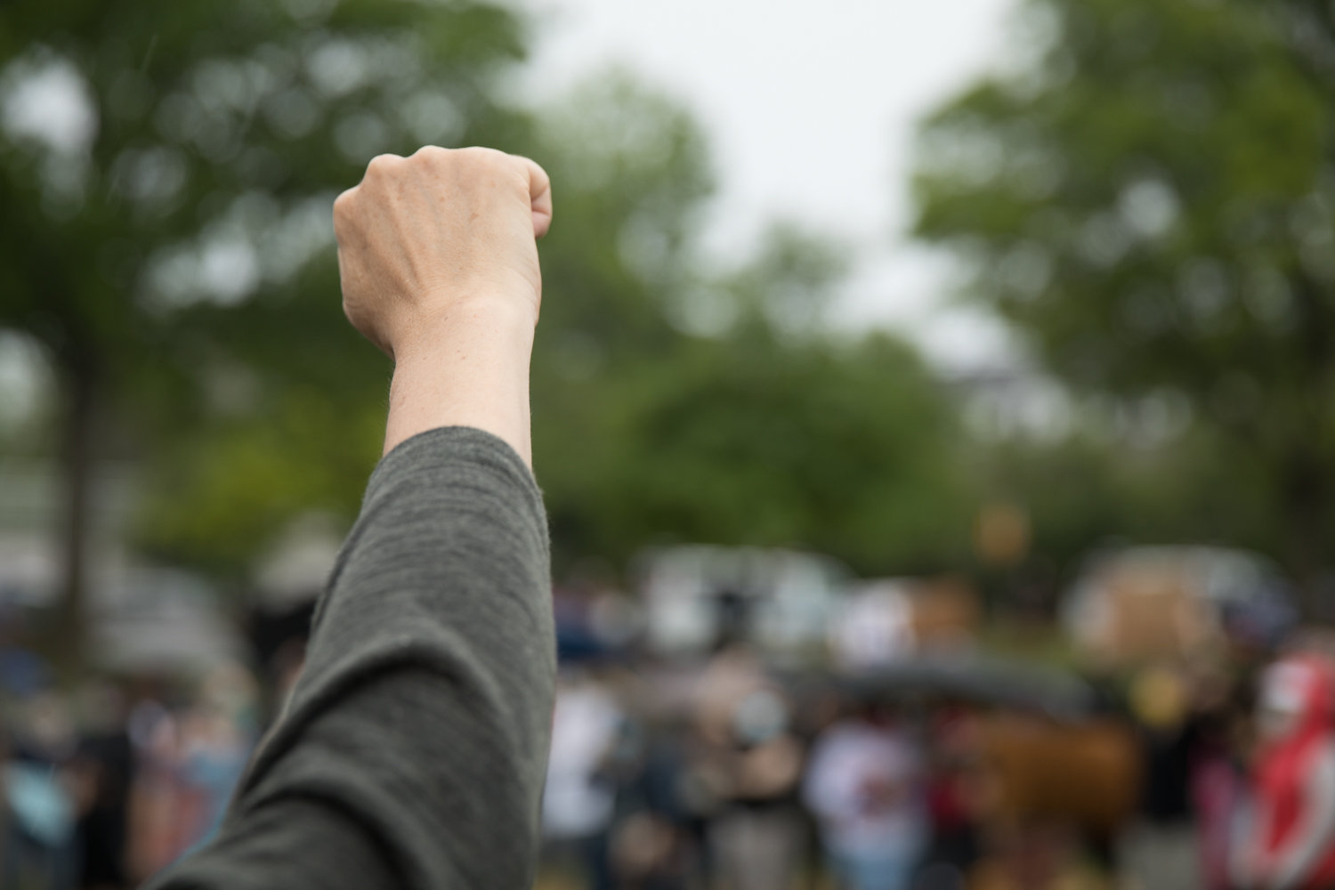 A community member raises her fist at a vigil in Seton Park honoring the lives of African Americans who died as a result of police brutality. The peaceful gathering was organized following rumors of a violent protest planned for the park that turned out to be untrue.