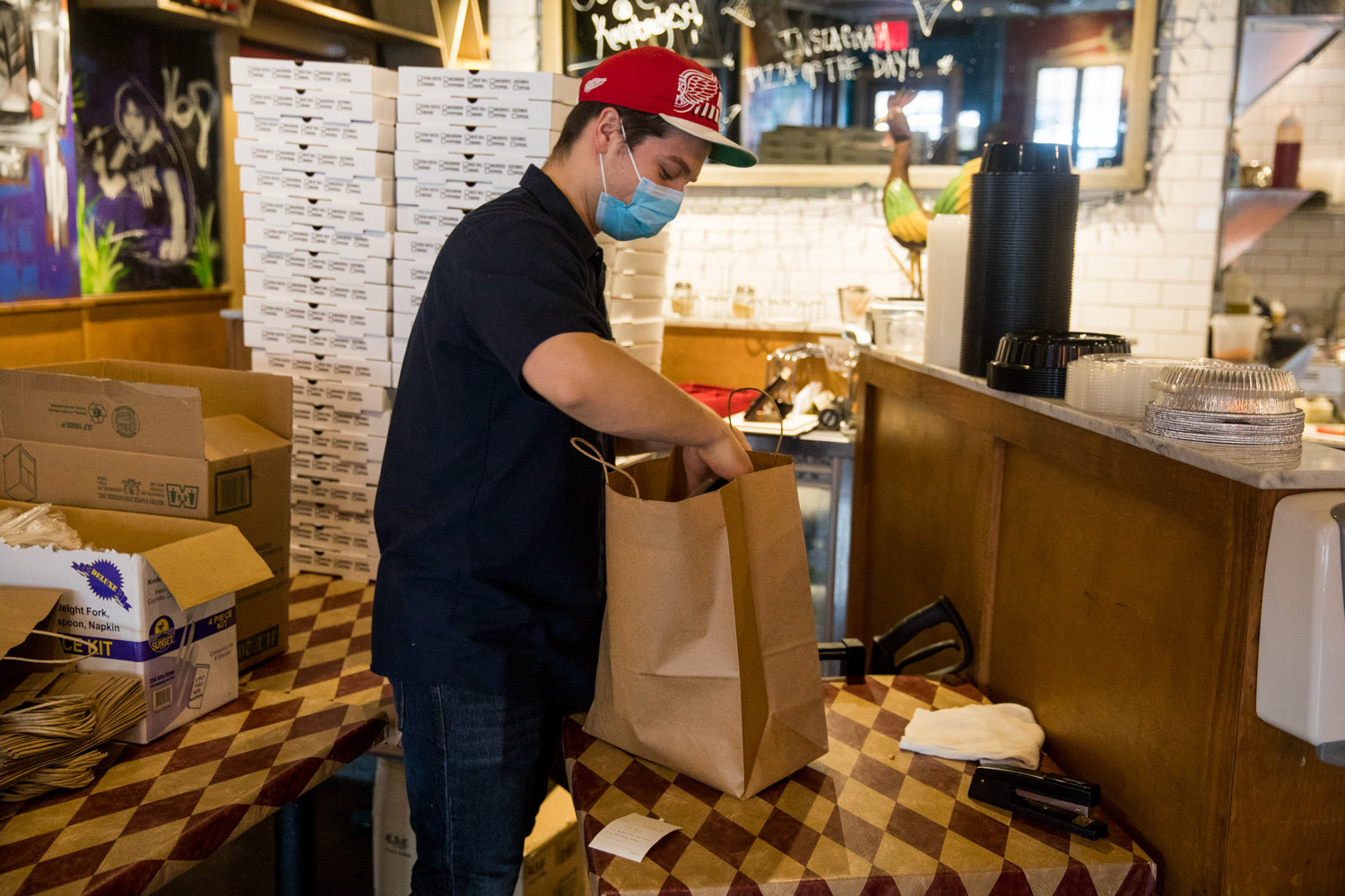 Ben Avery bags a customer’s order inside Kingsbridge Social Club, which has managed to stay in business despite the coronavirus pandemic. Restaurants have been moved up to the second phase of the state’s reopening plan for the city, but that will require outdoor seating.