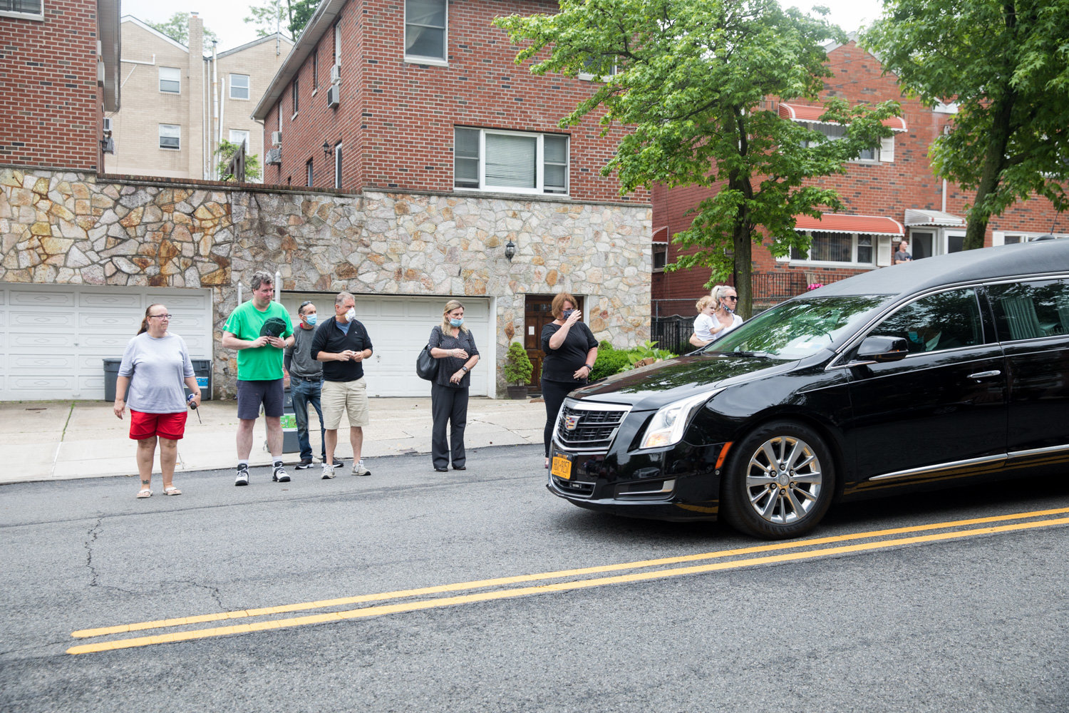 Mourners watch as a hearse carrying the late Michael Rooney makes its way down Mosholu Avenue where Rooney lived. A lifelong Riverdale resident, Rooney died June 3 at 65.