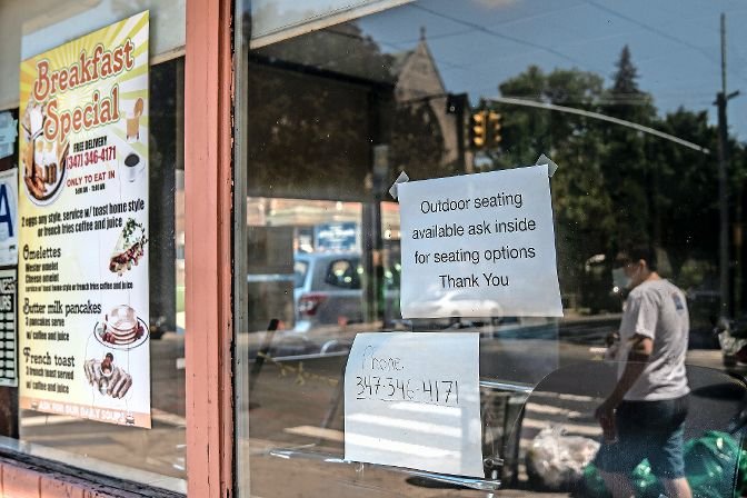 A sign at the Kingsbridge Donut Shop directs customers to outdoor seating if they want to stay at the restaurant with their food. The shop is struggling to stay afloat while serving mostly takeout and delivery orders, as many of their customers love to sit inside to catch up with friends and neighbors.