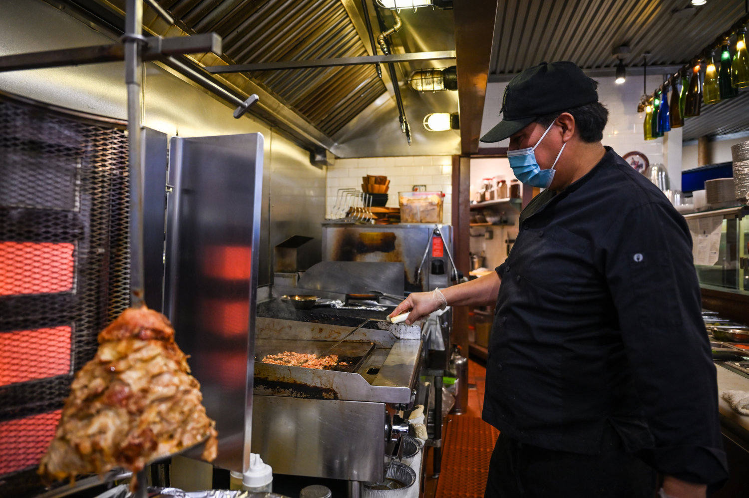 A cook at Taste & Sabor prepares meat for a salad bowl at the West 231st Street eatery. While the eatery is known for its Latin and Greek fare, some neighbors in need have discovered that when Taste & Sabor receives more food than it needs, it’s willing to share.