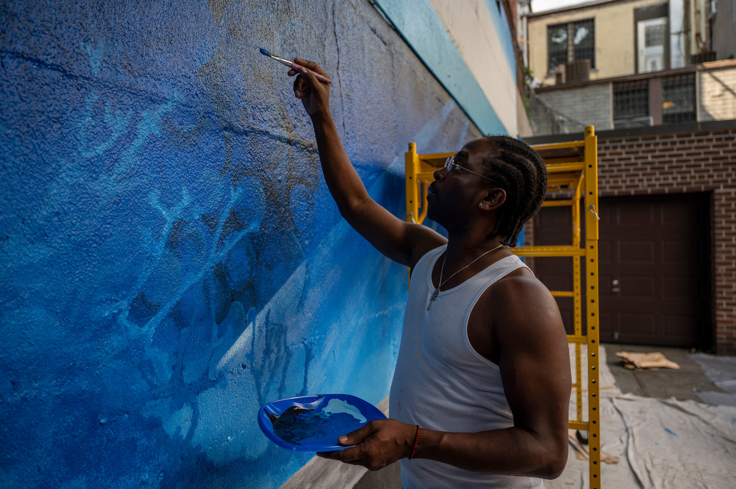 Olugbala Williams paints a mural on the back retaining wall of 3636 Greystone Ave. Nicky Enright was commissioned to paint this mural, ‘Aquarium,’ by his building’s co-op board because he’s no stranger to mural painting.