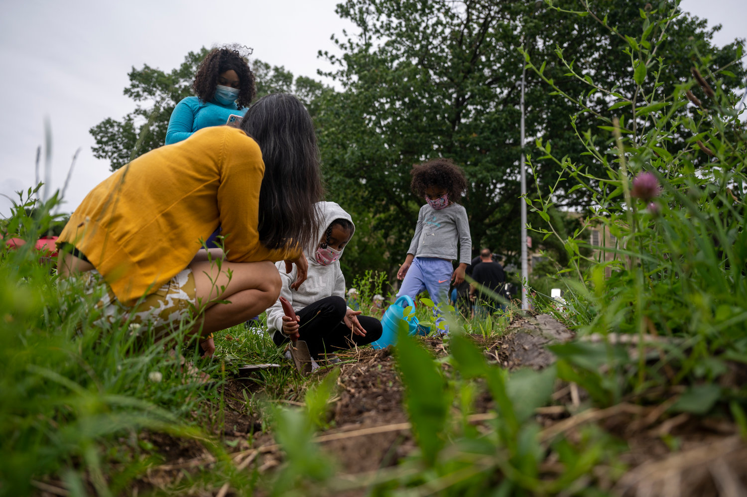 Women and children plant new flowers in the garden next to Sunday farmers market outside of Clinton High School.