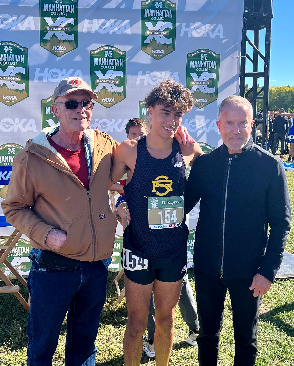 Dave Sandridge, left, and Gene McCarthy stand with Devan Kipyago of St. Raphael Academy, who took first place in the prestigious Boys Eastern States Championship. McCarthy, a longtime marketing and sales executive for Nike, won the inaugural race in 1973.