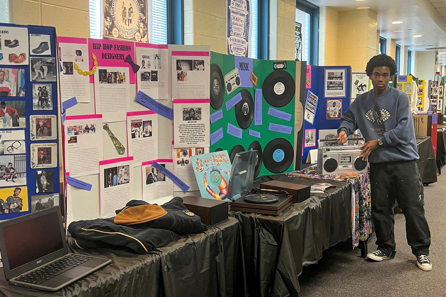 Mitchell Jefferson, president of the Black Student Union & Allies Club at Riverdale / Kingsbridge Academy, worked together with his club mates led by librarian Julia Loving to honor the history of hip-hop as it turns 50 this year. On the table is clothing, a boom box, and a record player complete with top rap hits.