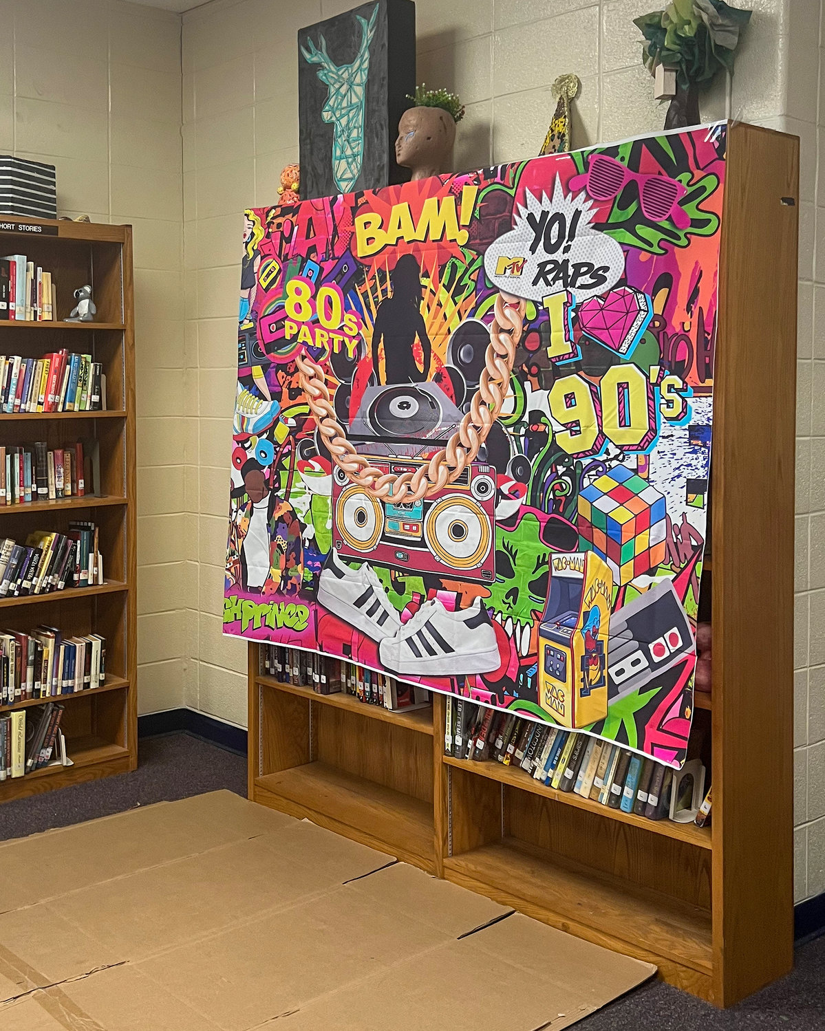 A backdrop where students posed to take pictures while wearing jewelry, hats, jackets and music props from the hip hop era. The cardboard on the floor was created for breakdancing.