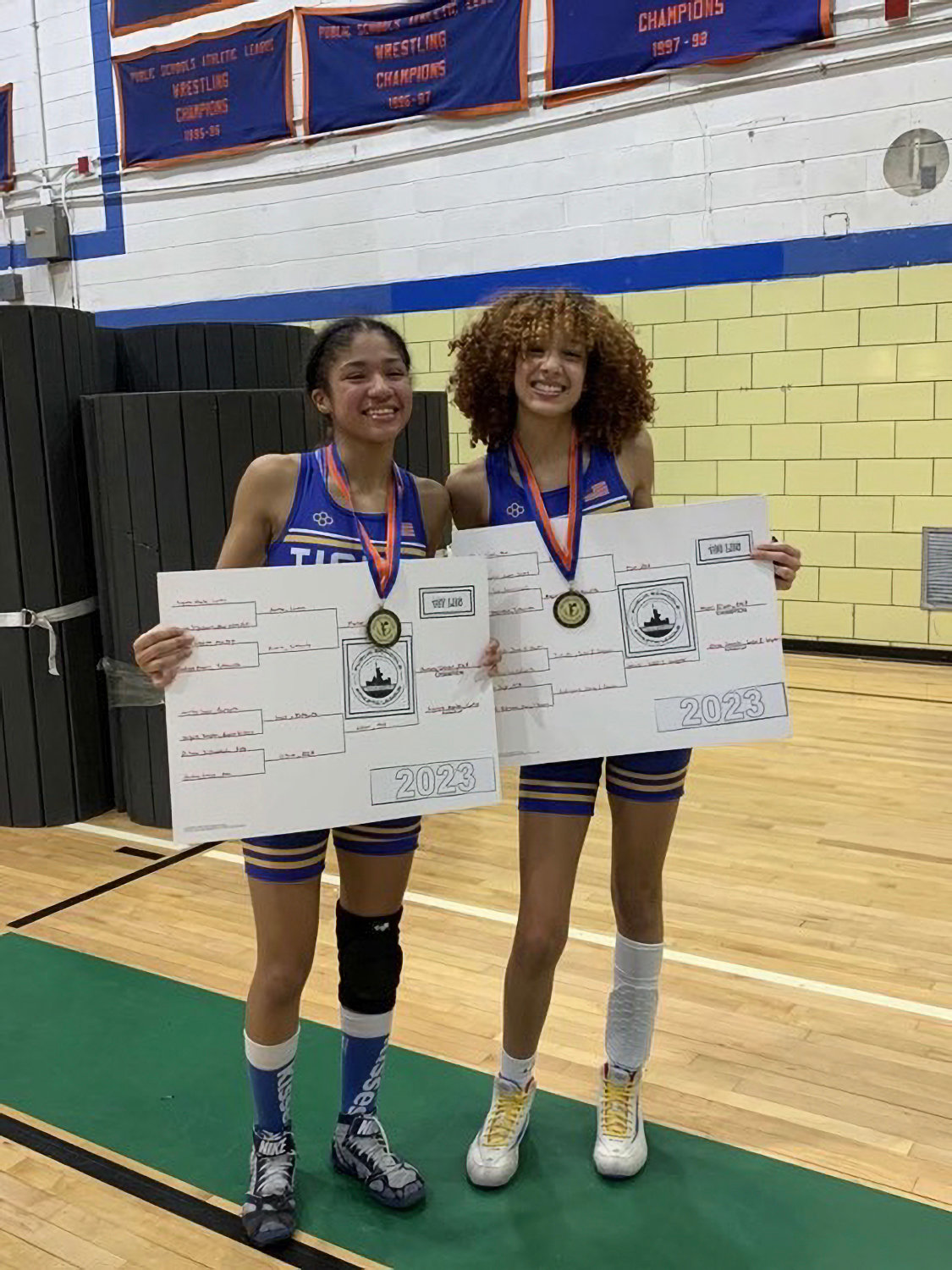 Lexi Elson and Destiny Gibson-Brown holding their bracket cards during a recent wrestling match. The two have been pioneers as female wrestlers on the boys high school team.