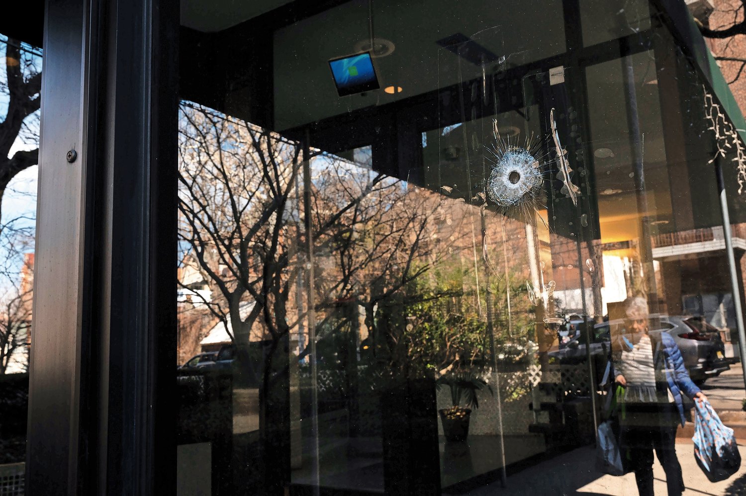 Bullet holes on the principal entrance of 3800 Waldo Gardens on Wednesday, March 22.