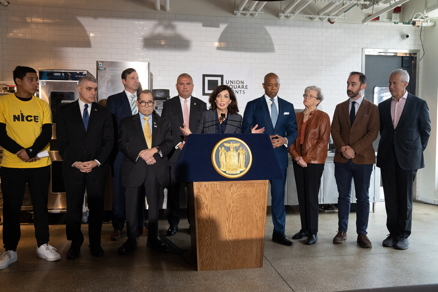 Governor Kathy Hochul takes the podium beside Mayor Eric Adams at a joint press event at Industry City in Brooklyn Monday, May 22 to push for faster work authorization for asylum seekers. The governor and mayor are calling on the Biden administration to take executive action to speed up the waiting period for asylum seekers to work legally.