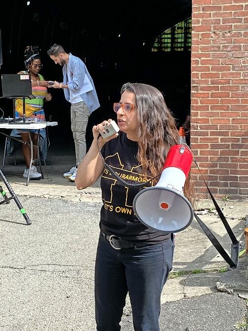 Sandra Lobo, executive director of the Northwest Bronx Community and Clergy Coalition and co-chair of Together for Kingsbridge group uses a megaphone Sunday to get her points across to the crowds at the armory.