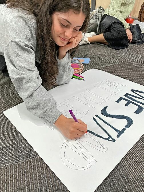 A student draws on a sign she made that states, 'We Stand with Israel,' at SAR High School prior to the Tuesday march on Washington, D.C.